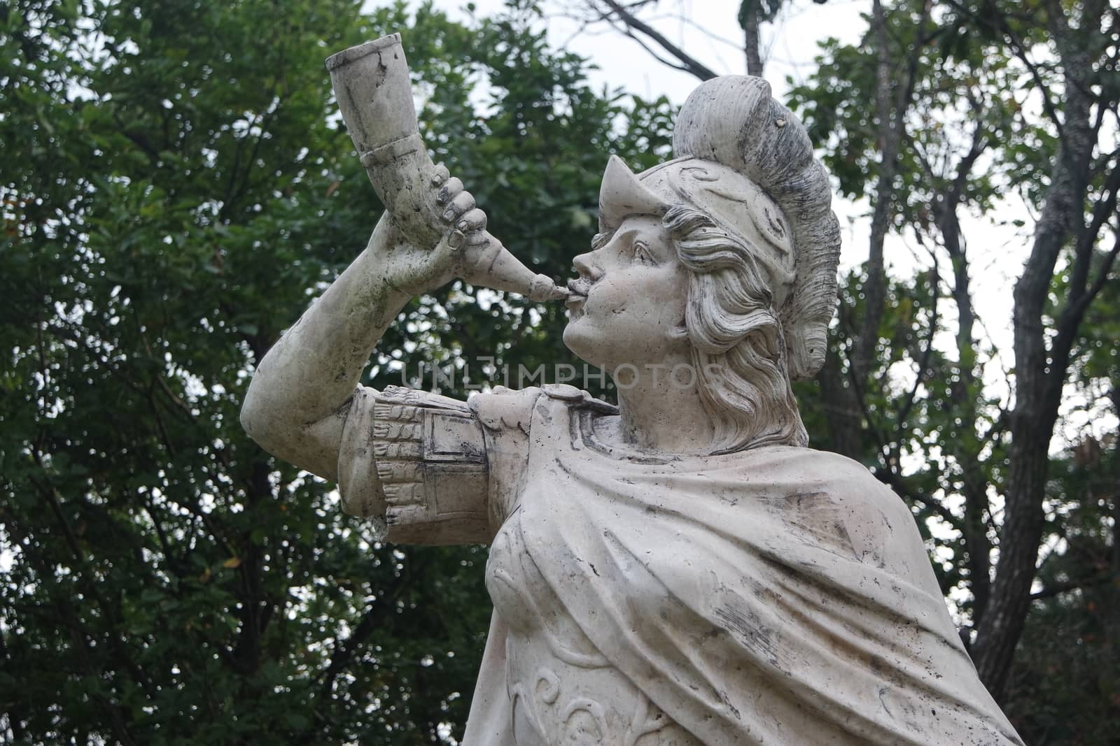 sculpture of classical water god blowing conch shell - ancient natural trumpet. Stone sculpture of a Triton, blowing on his conch shell trumpet.