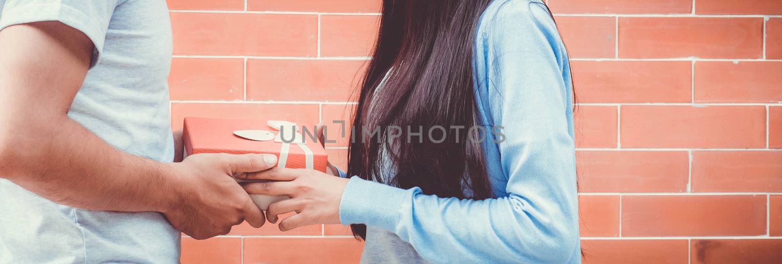 Asian couple young man giving gift to woman outdoors. Happy fami by nnudoo