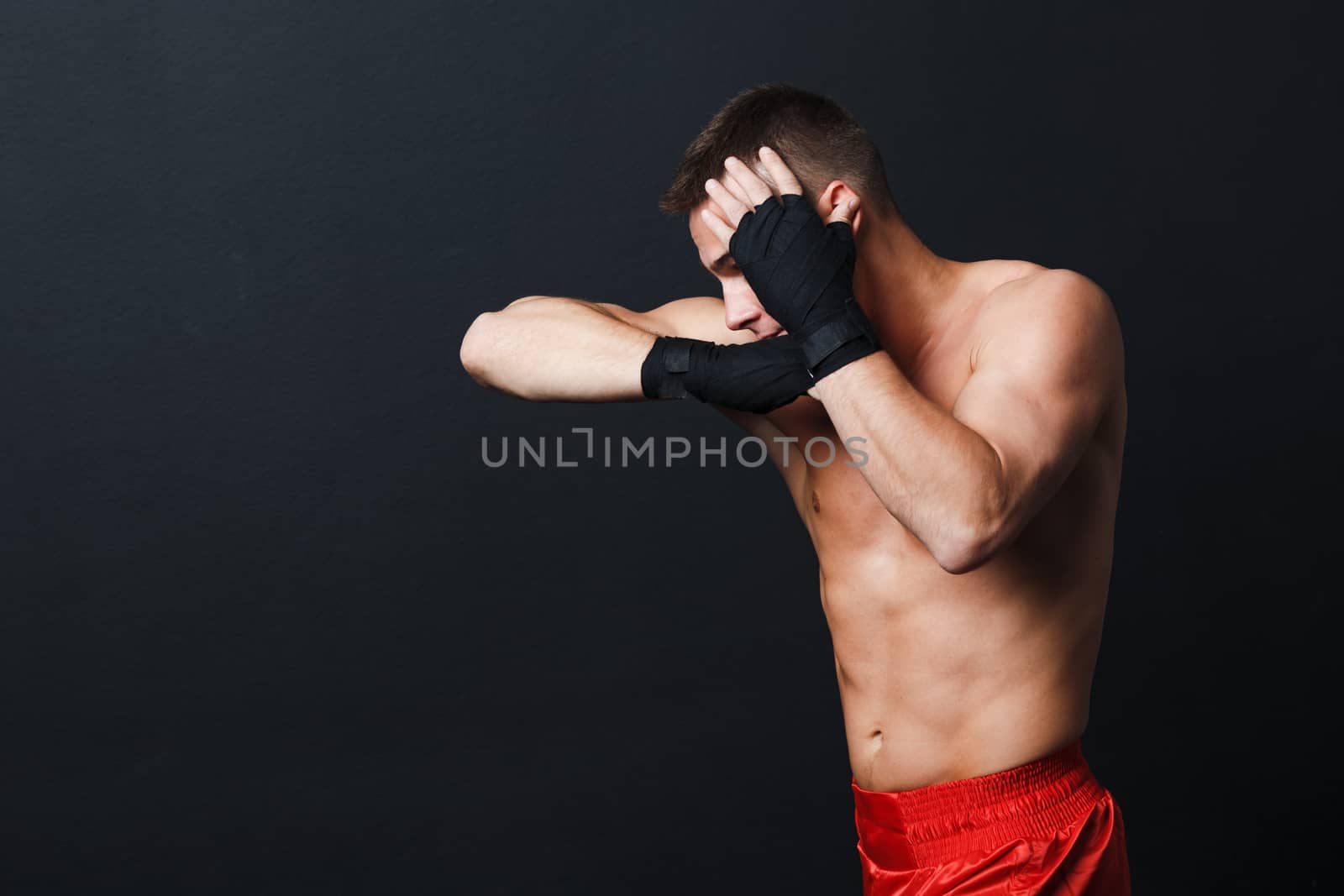 Sportsman muay thai man boxer stance ad elbow punch at black background.