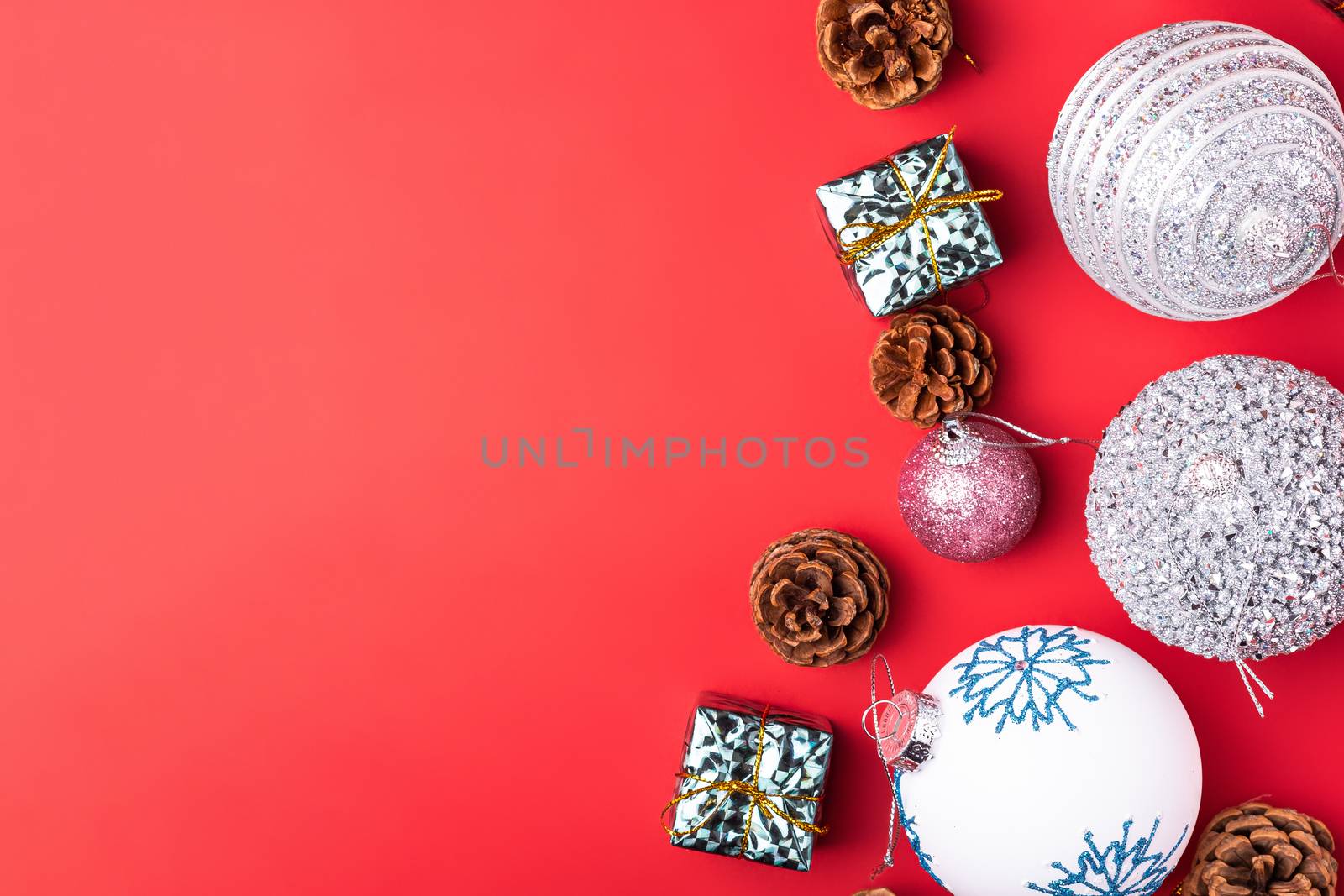 Christmas New Year composition. Gifts, fir tree cones, silver ball decorations on red background. Winter holidays concept. Flat lay, top view, copy space