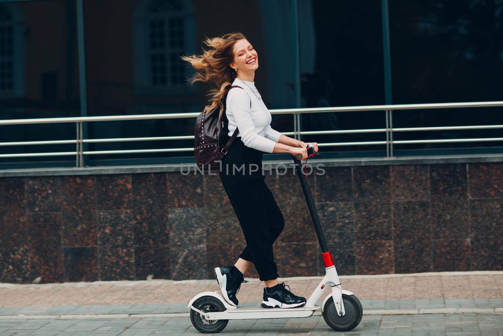 Young woman with electric scooter at the city by primipil