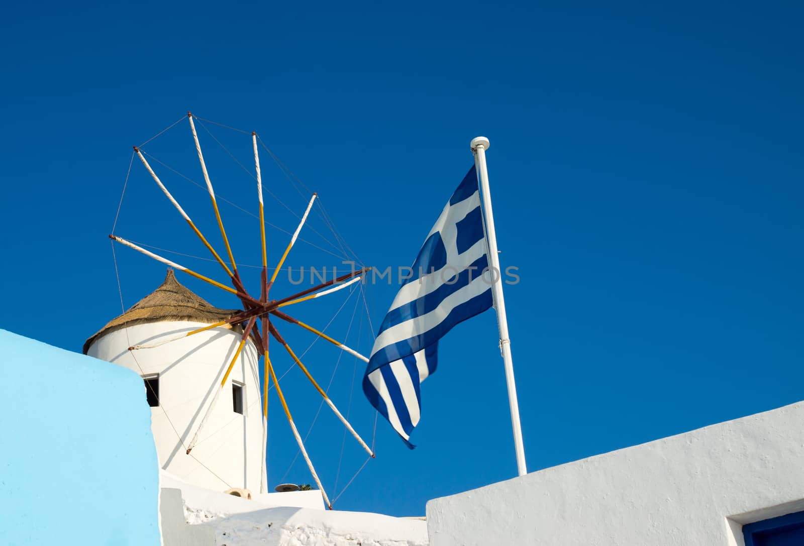 A typical windmill and a greek flag seen on Santorini island