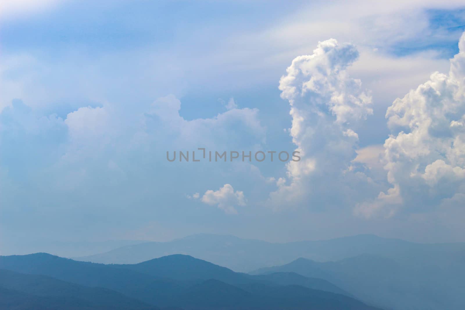 Mountains and hills in the distance. Blue silhouette of a mountain in the distance, with clouds in the blue sky. by mahirrov