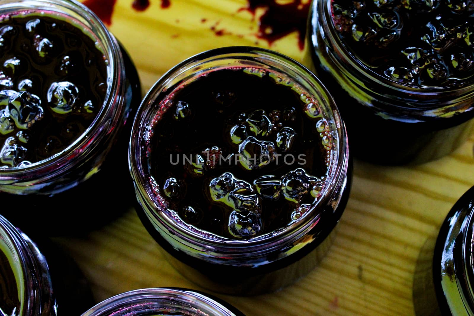 The process of filling homemade chokeberry jam on a tray. Jars full of chokeberry jam, ready to close. Aronia. Zavidovici, Bosnia and Herzegovina.