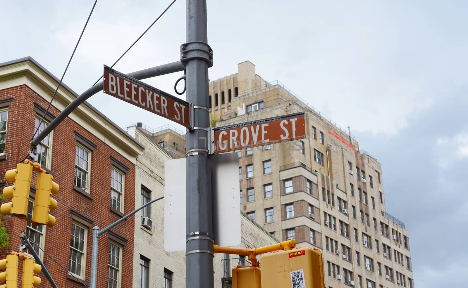 Street signs in New York City for Bleecker Street and Grove Street on a traffic light pole. Apartment buildings beyond.