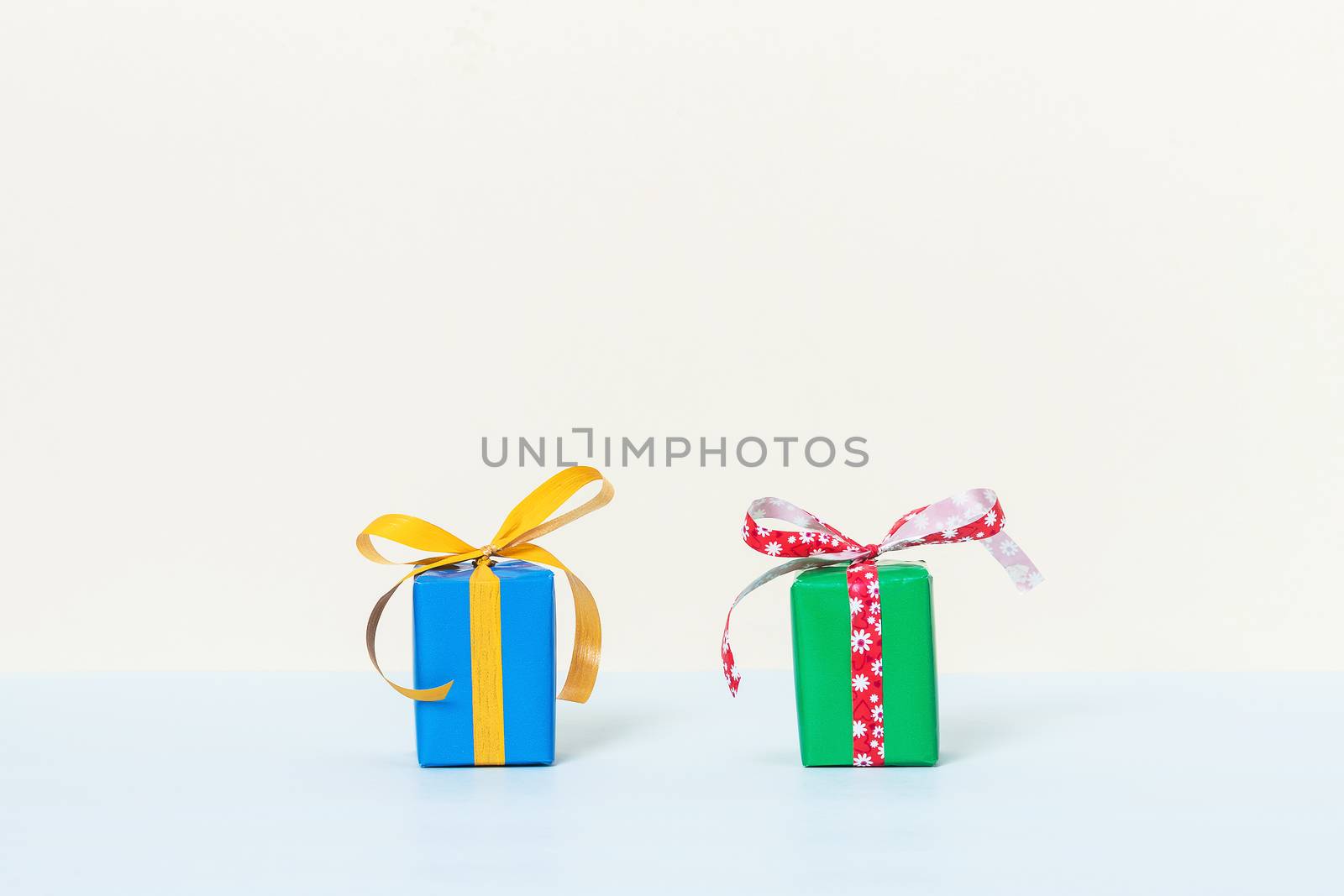 Two colorful gift boxes on a pastel background with space for your text. Front view.