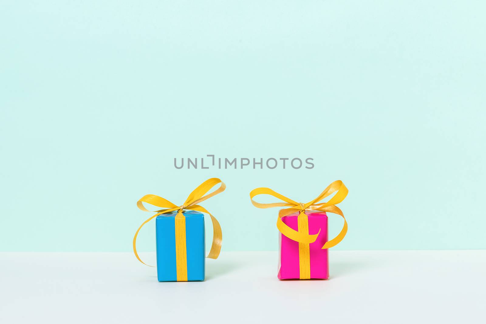 Two colorful gift boxes on a pastel background with space for your text. Front view.