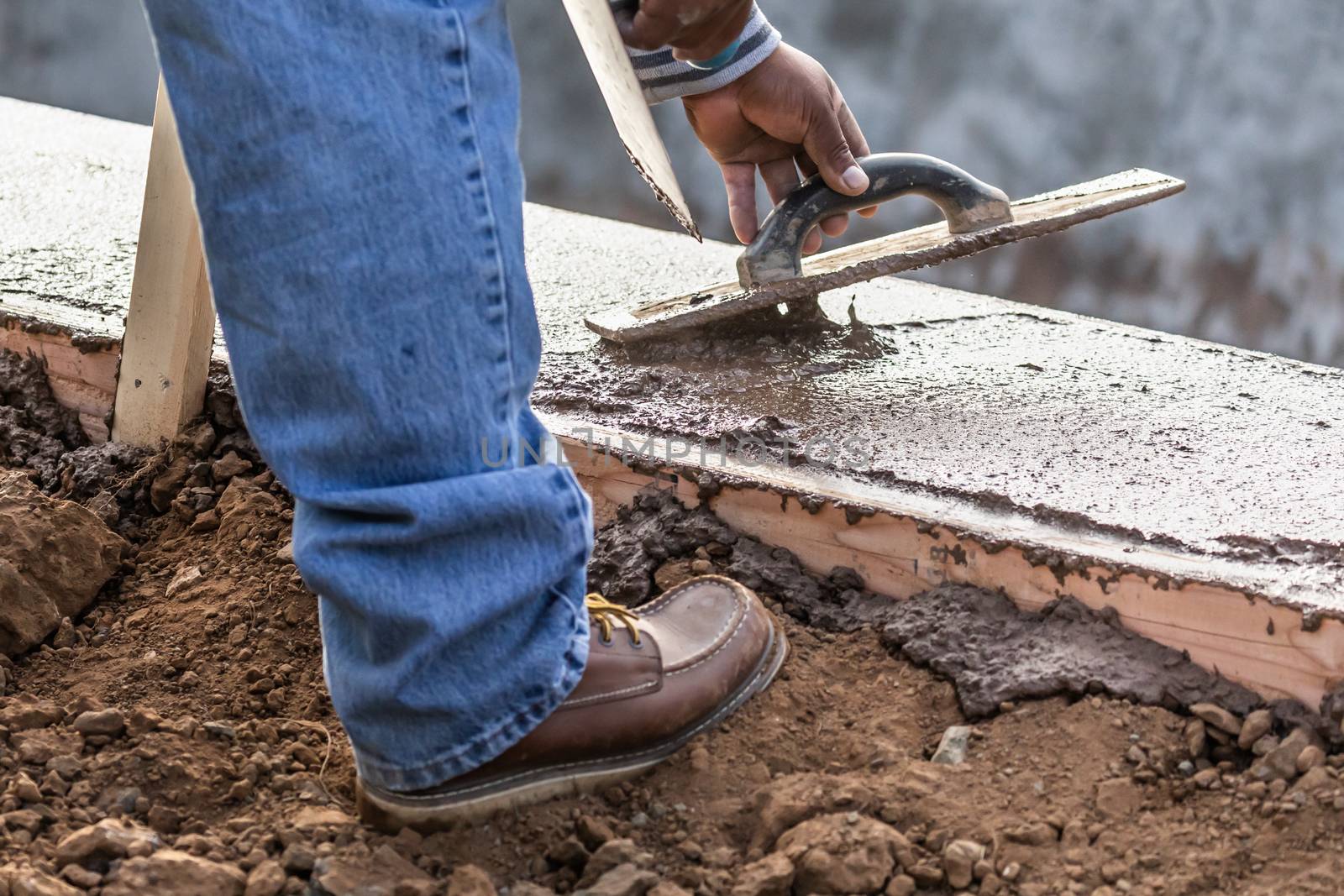 Construction Worker Using Wood Trowel On Wet Cement Forming Copi by Feverpitched