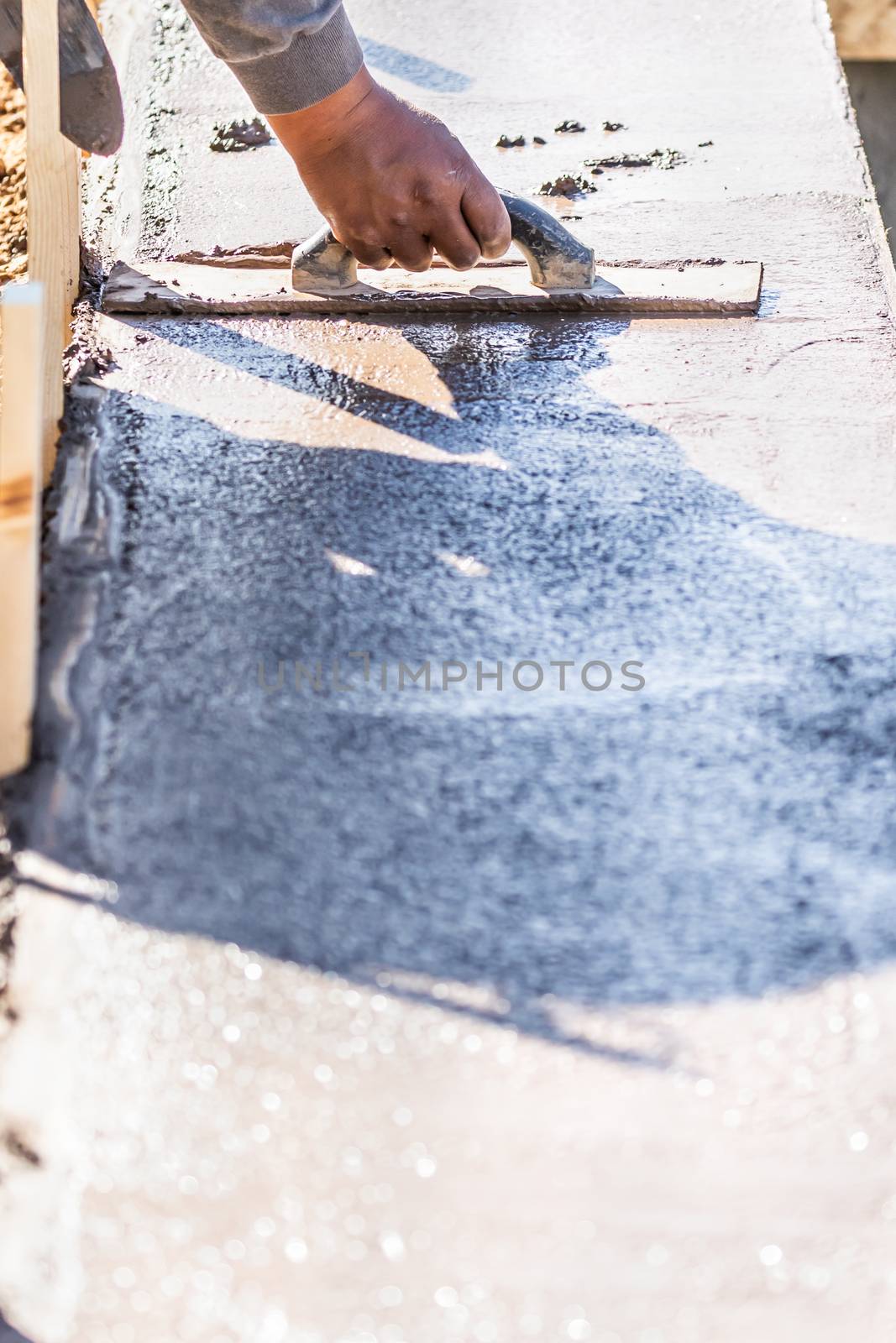 Construction Worker Using Wood Trowel On Wet Cement Forming Copi by Feverpitched