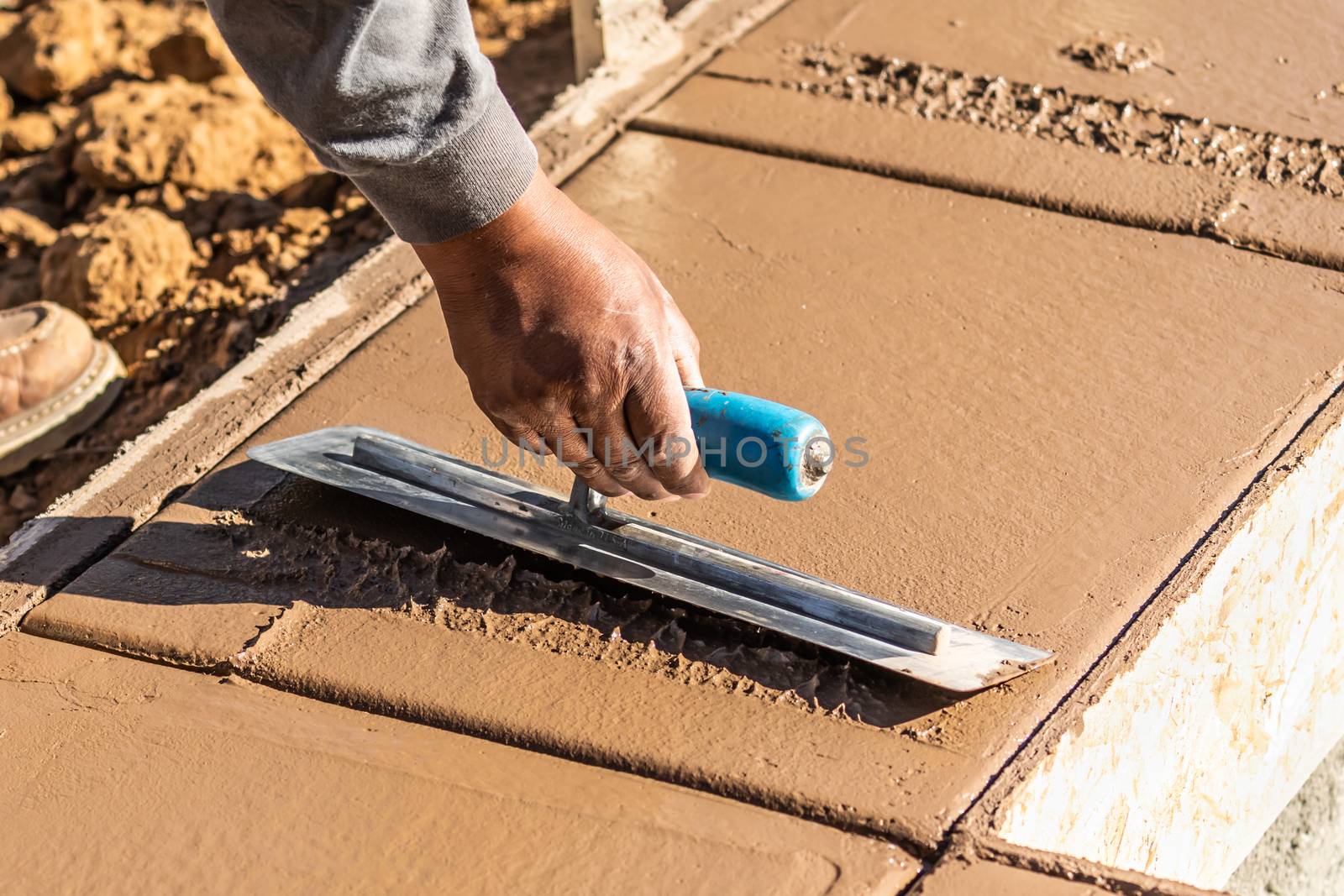 Construction Worker Using Trowel On Wet Cement Forming Coping Ar by Feverpitched