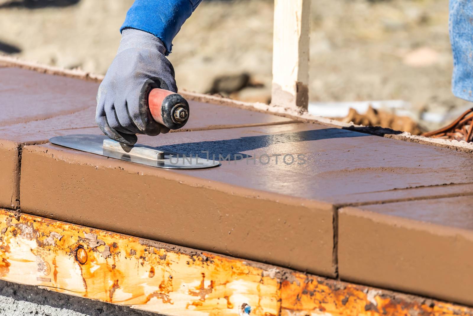 Construction Worker Using Trowel On Wet Cement Forming Coping Ar by Feverpitched