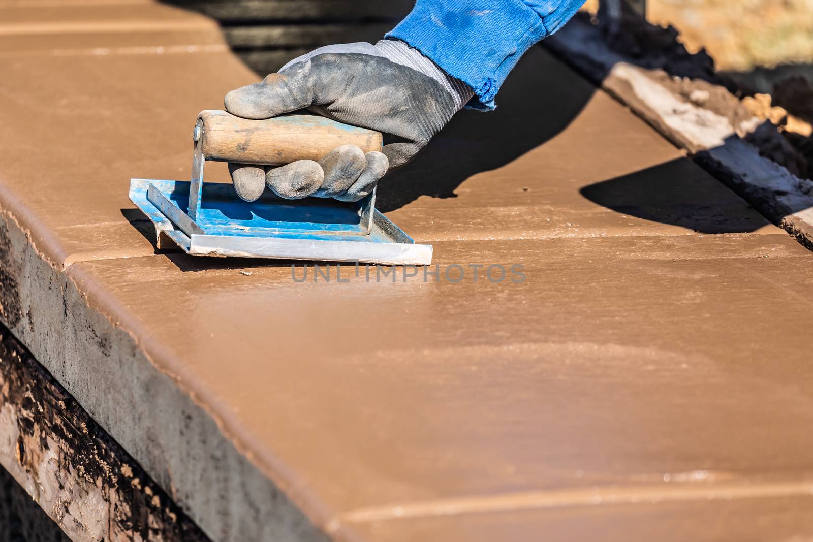 Construction Worker Using Hand Groover On Wet Cement Forming Coping Around New Pool.