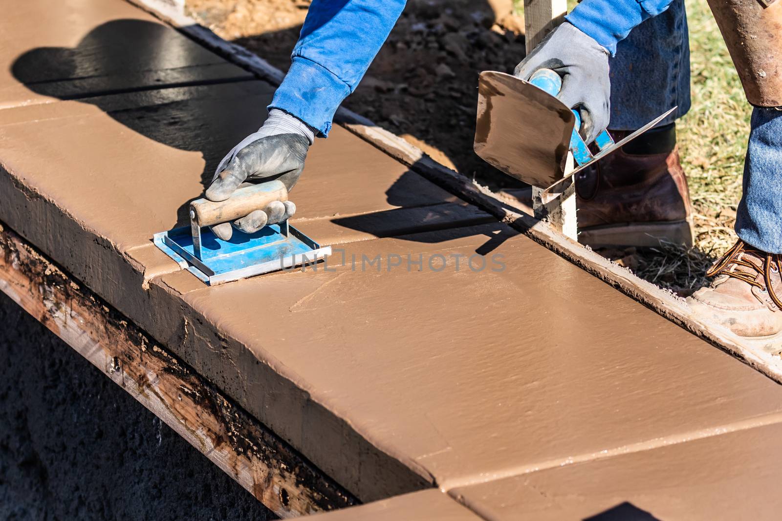 Construction Worker Using Hand Groover On Wet Cement Forming Coping Around New Pool.