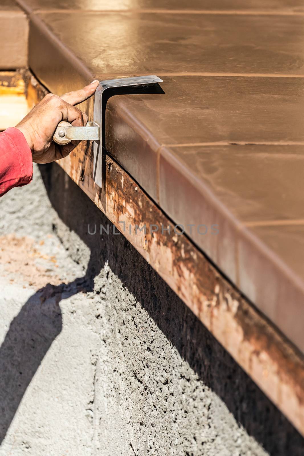 Construction Worker Using Stainless Steel Edger On Wet Cement Forming Coping Around New Pool.