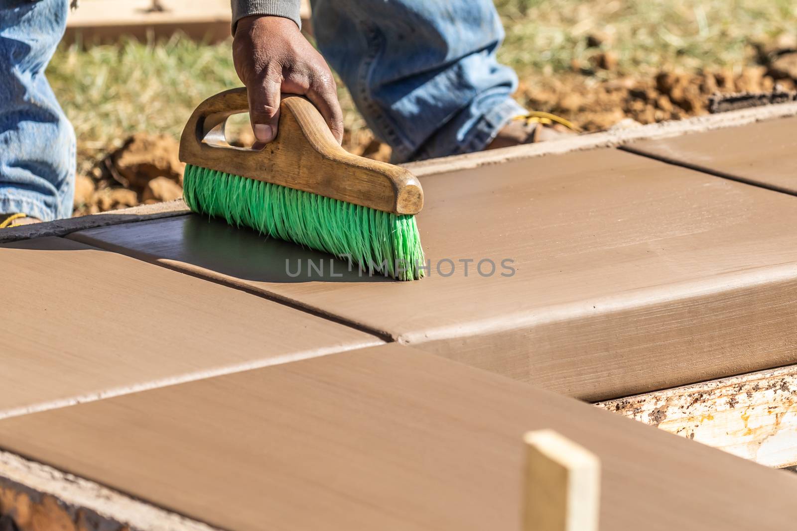 Construction Worker Using Brush On Wet Cement Forming Coping Around New Pool.