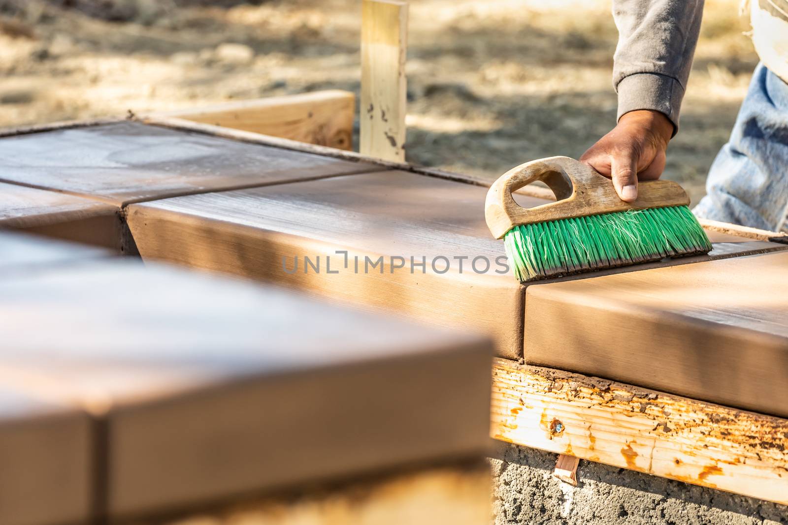 Construction Worker Using Brush On Wet Cement Forming Coping Aro by Feverpitched