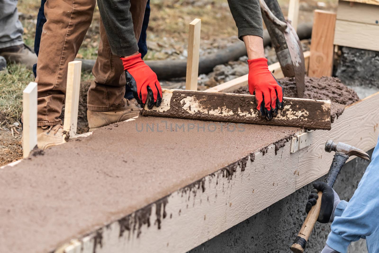 Construction Worker Leveling Wet Cement Into Wood Framing by Feverpitched