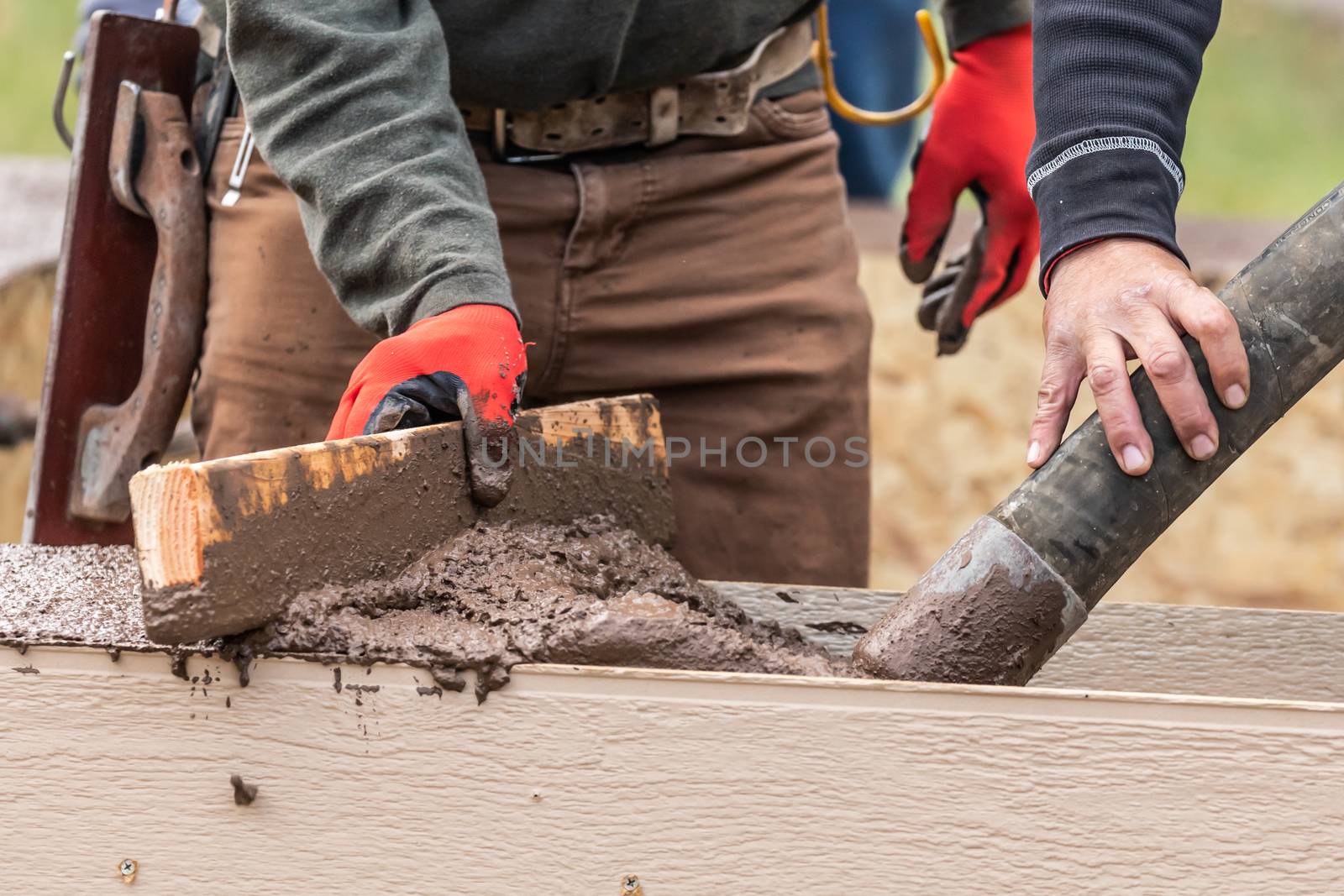 Construction Worker Leveling Wet Cement Into Wood Framing by Feverpitched