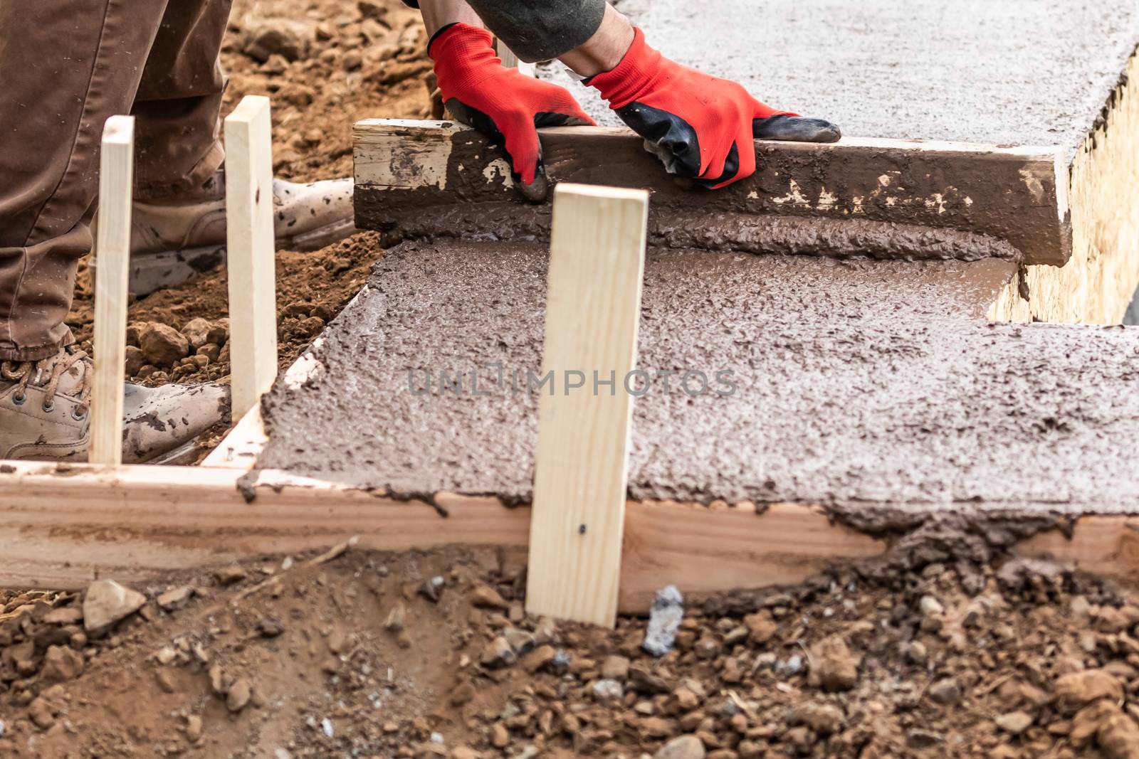 Construction Worker Leveling Wet Cement Into Wood Framing by Feverpitched