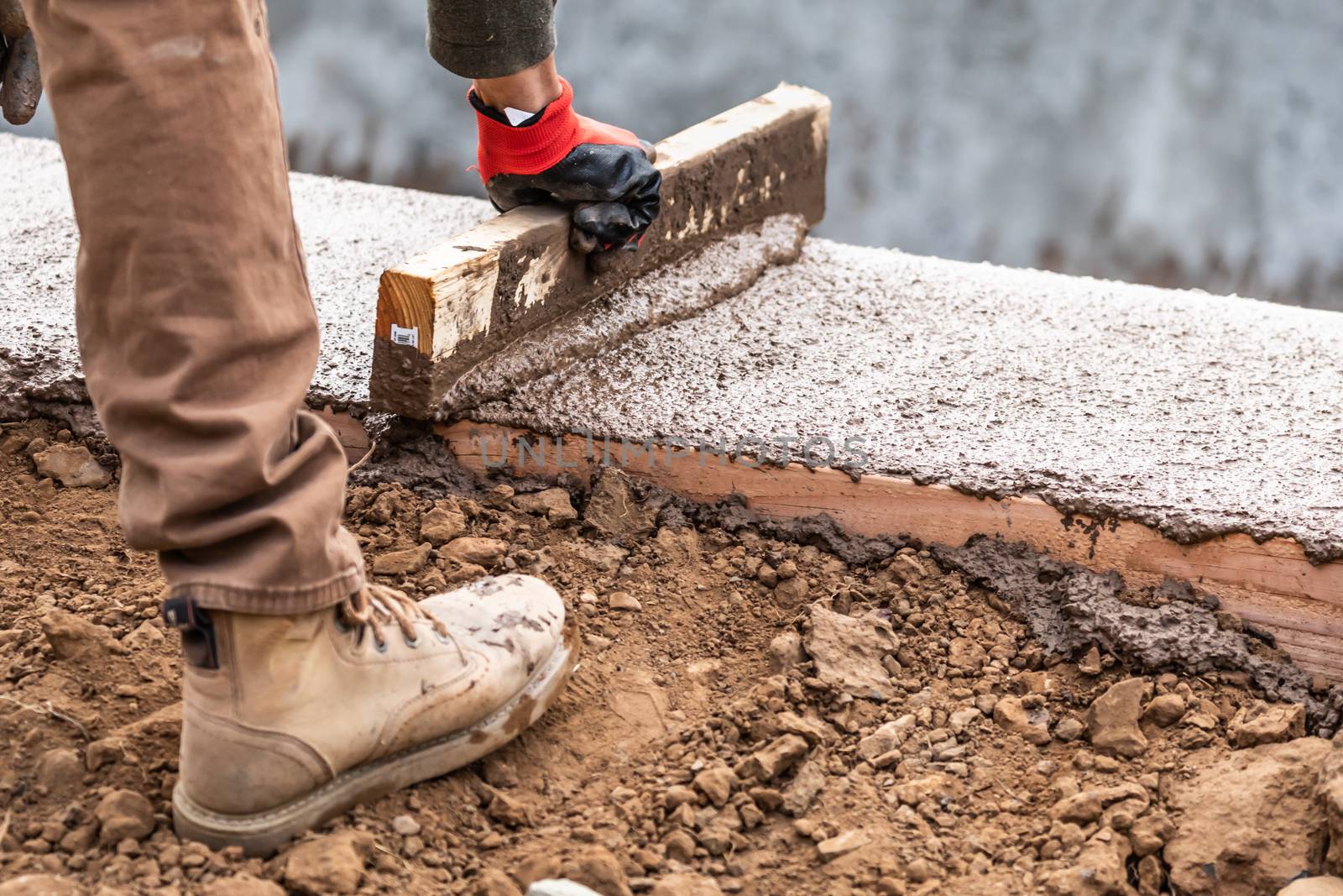 Construction Worker Leveling Wet Cement Into Wood Framing by Feverpitched