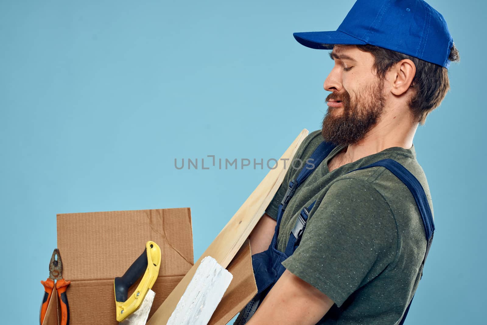 Worker man in uniform box tools construction blue background. High quality photo