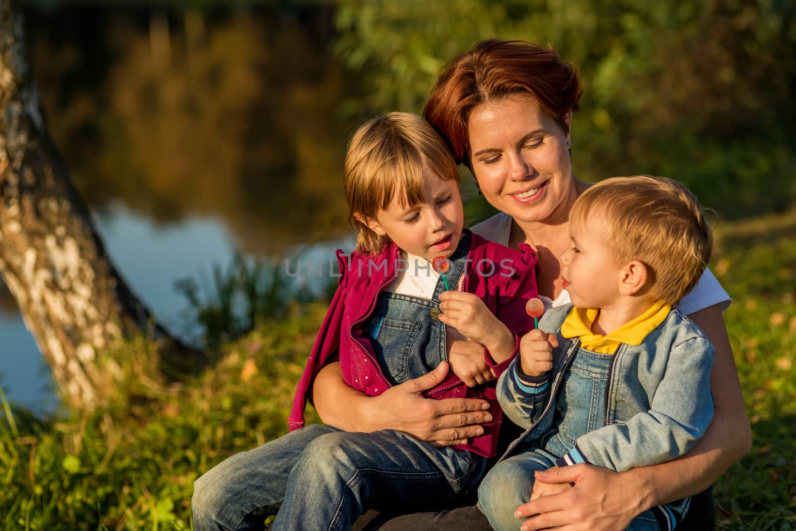 happy family Mom and children sit on the river bank by galinasharapova