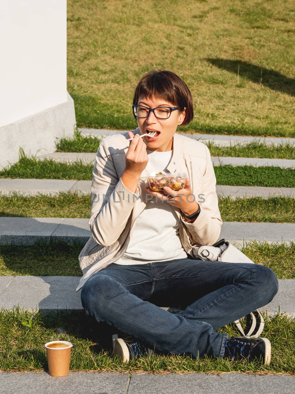 Woman sits on park bench with take away lunch box and cardboard by aksenovko