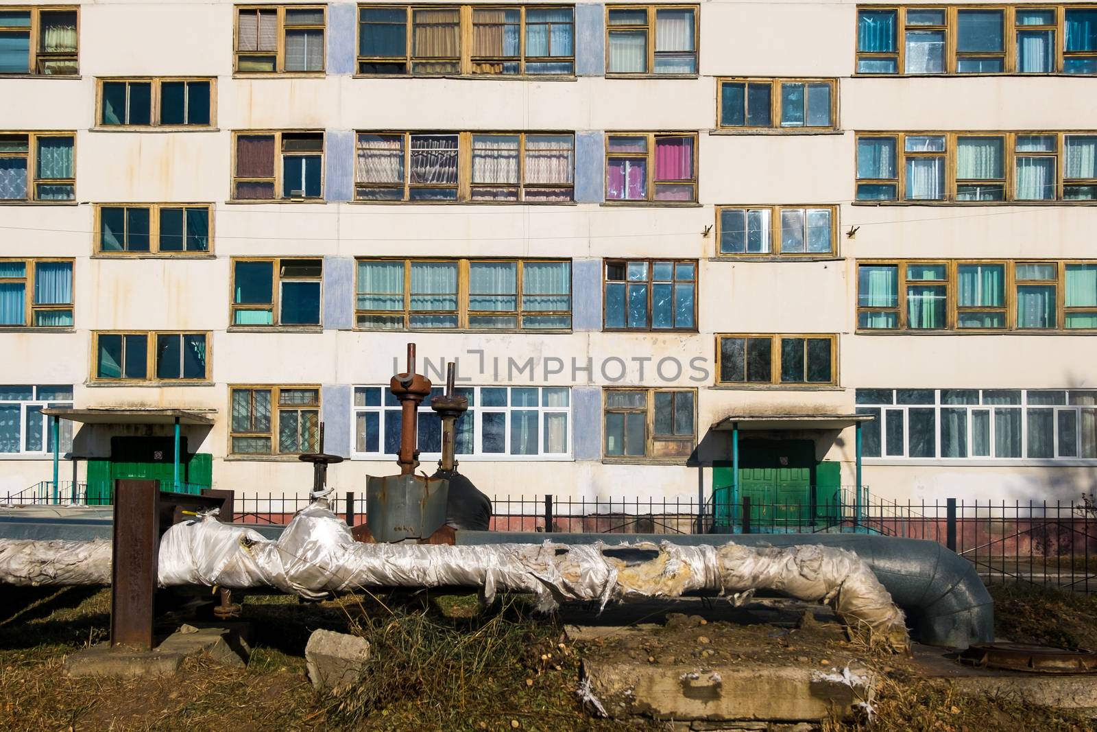 An apartment building in Russia stands in front of heating pipes.