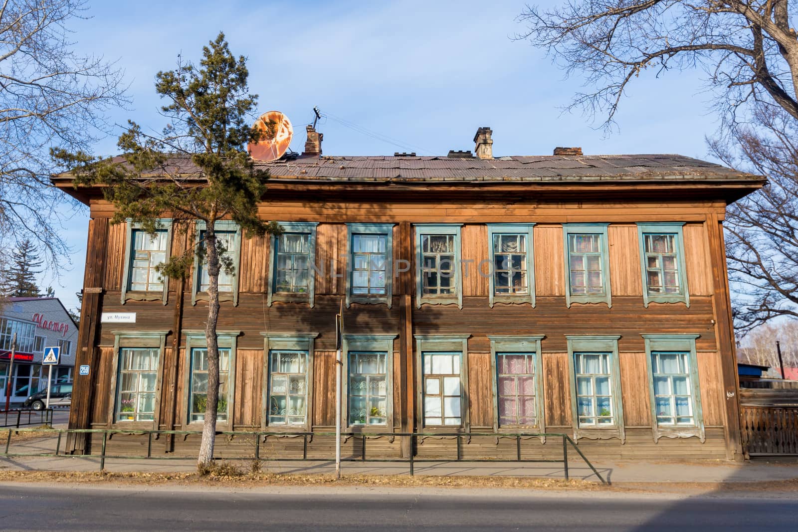 Old wooden residential two-storey house in the middle of a city street in Russia.