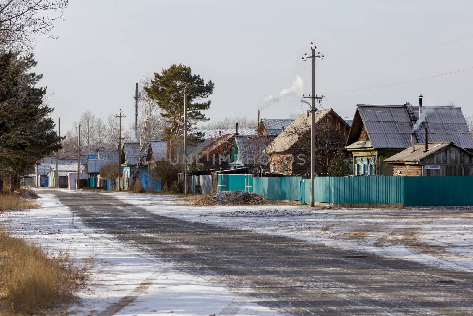 Street with wooden one-story houses in the Russian village.