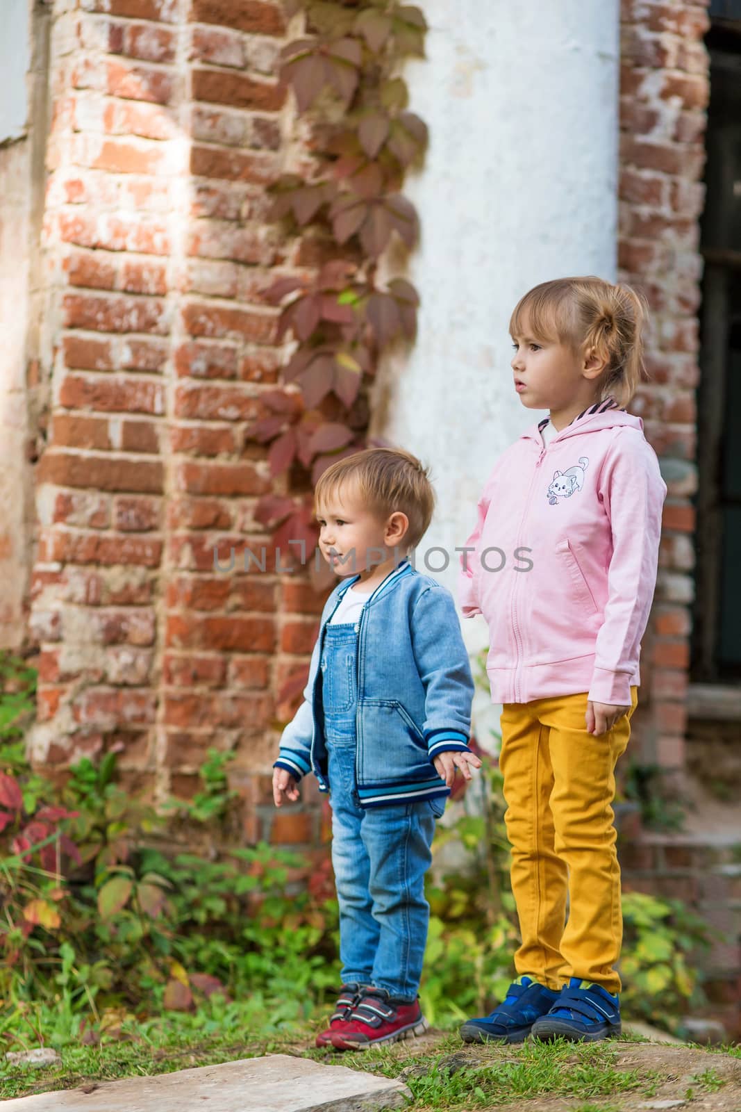 .Children stay near the column in the old park on an autumn walk.