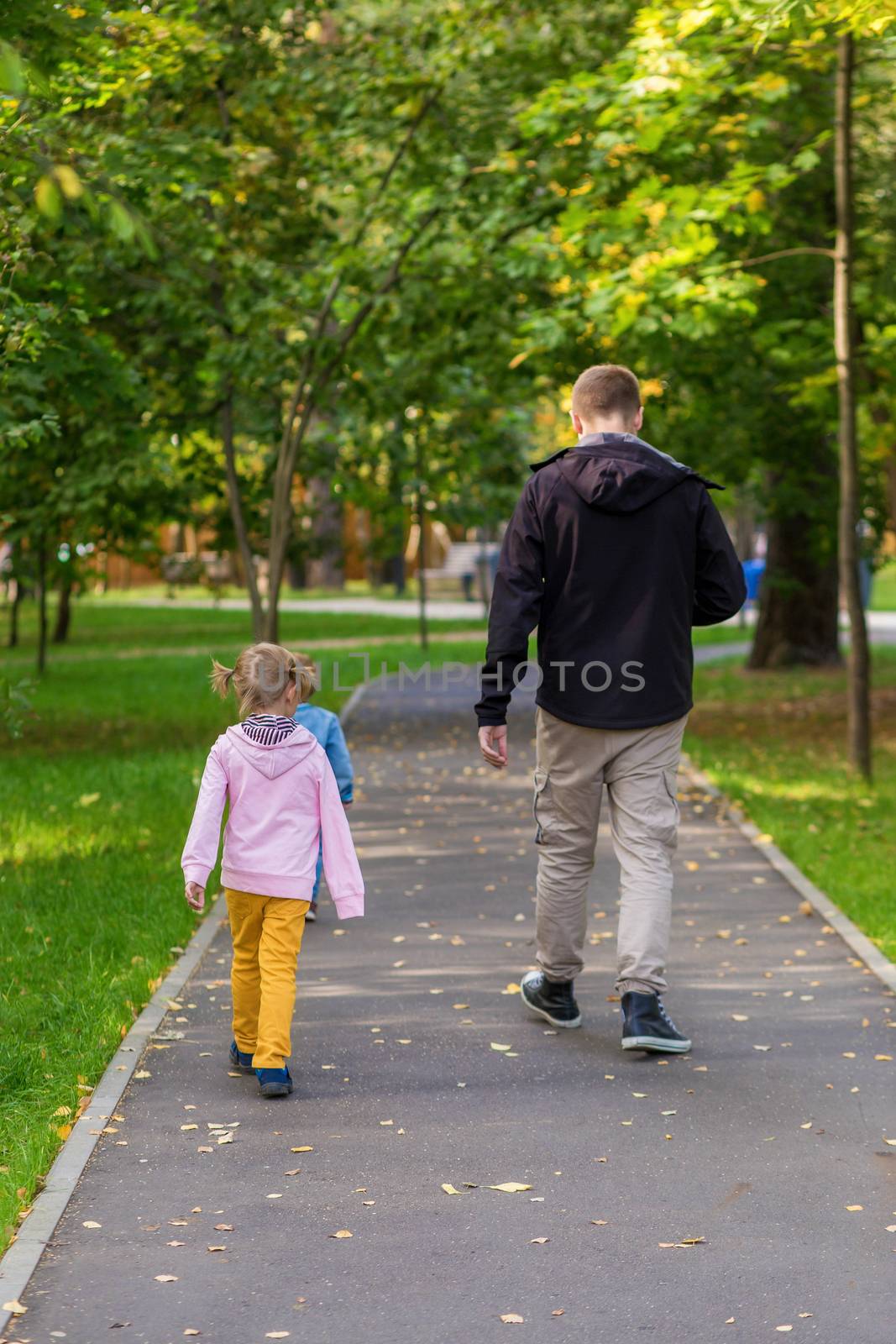 .Dad with children walking along the path in the park on an autumn walk. by galinasharapova