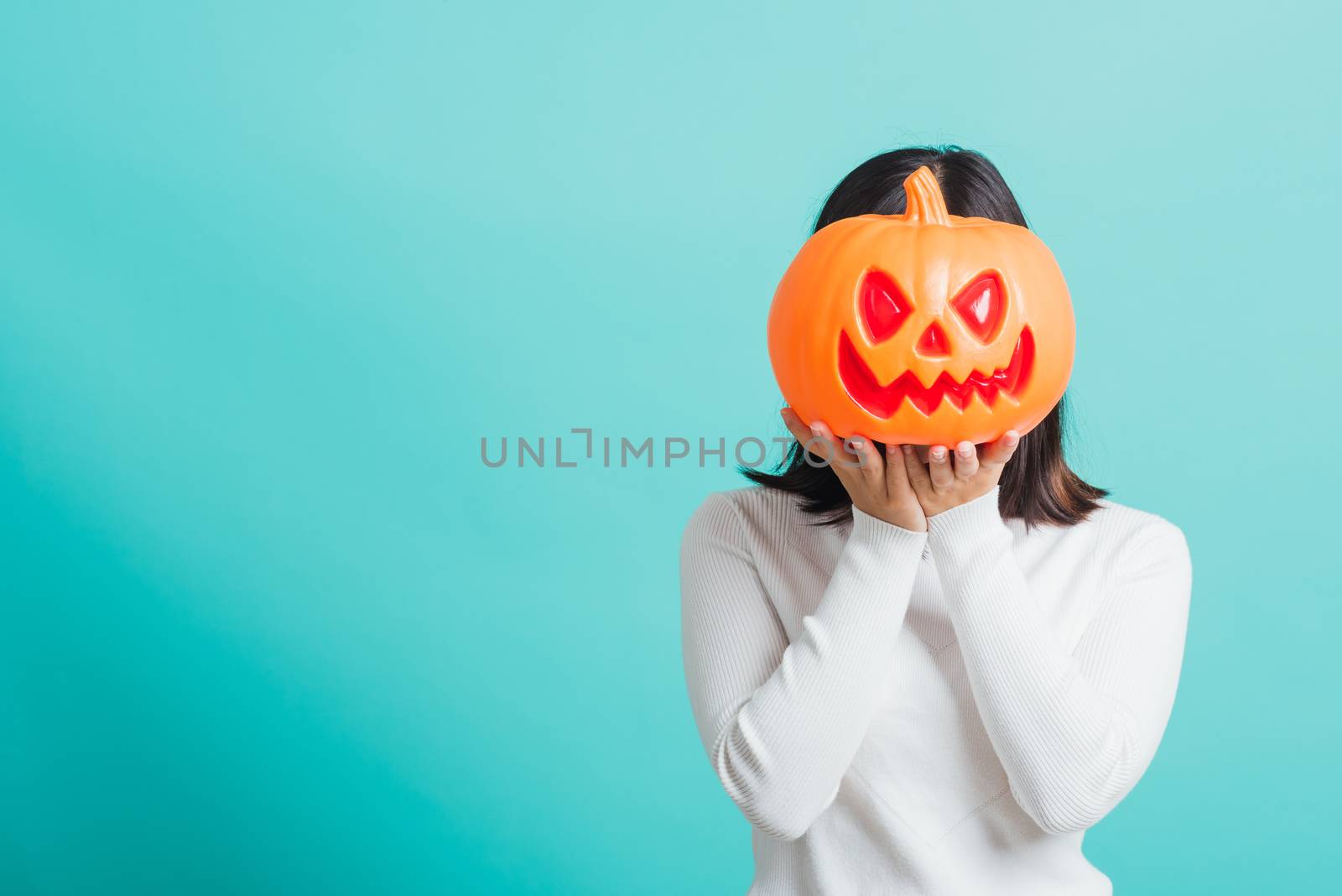 woman holding orange model pumpkins at her head by Sorapop
