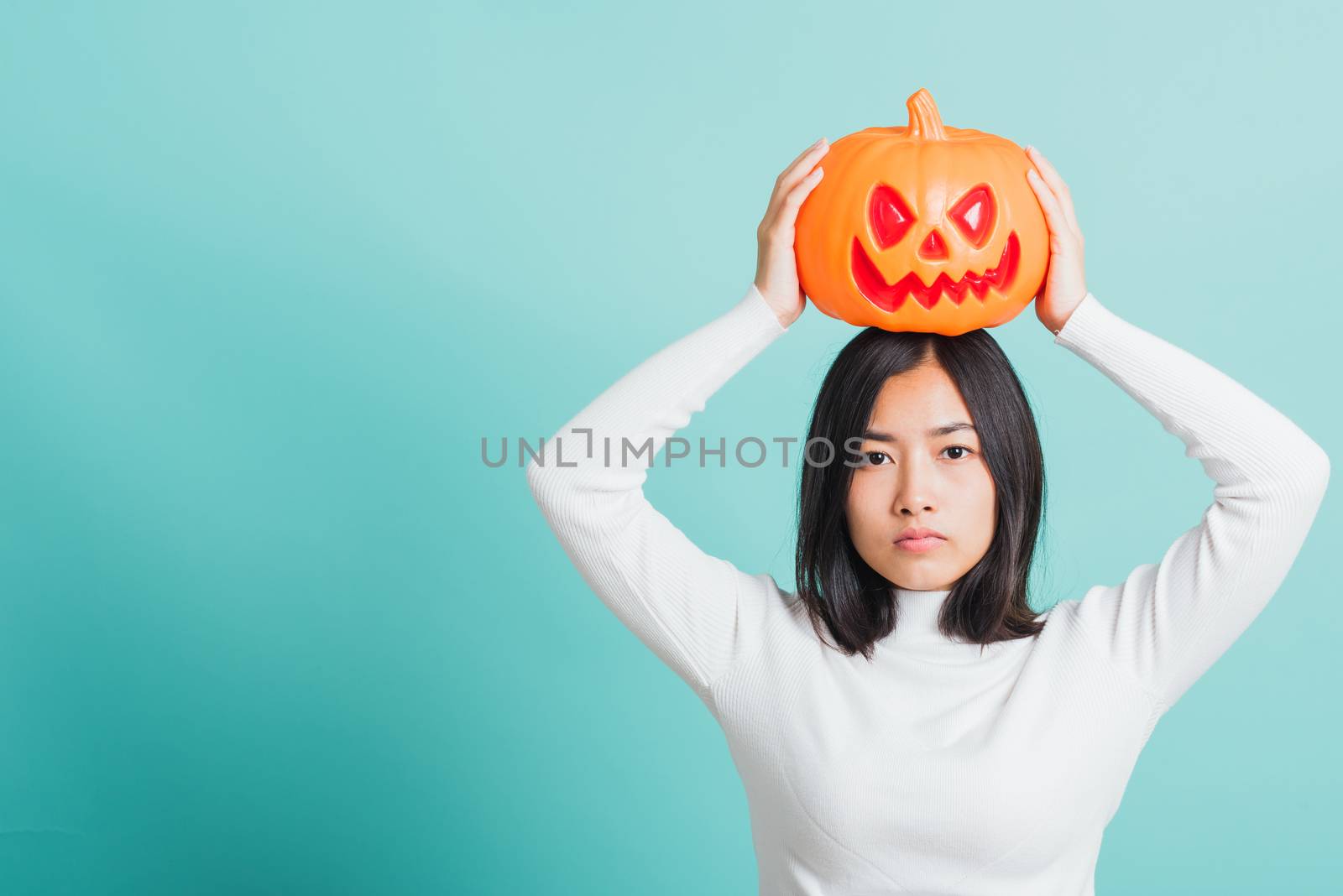 woman holding orange model pumpkins and put it on the head by Sorapop