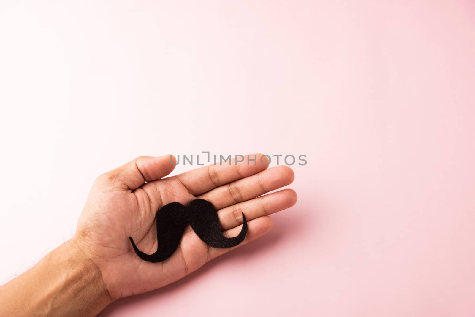 The man uses hand holding black mustache, studio shot isolated on white background, Prostate cancer awareness month, Fathers day, minimal November moustache concept