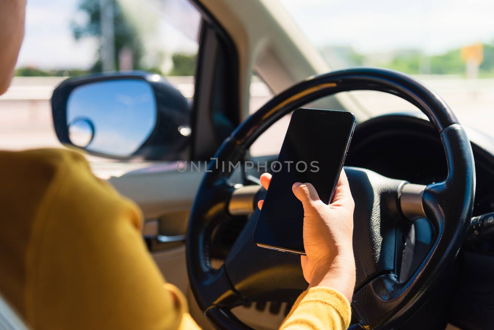 woman inside a car and using a hand holding mobile smartphone by Sorapop