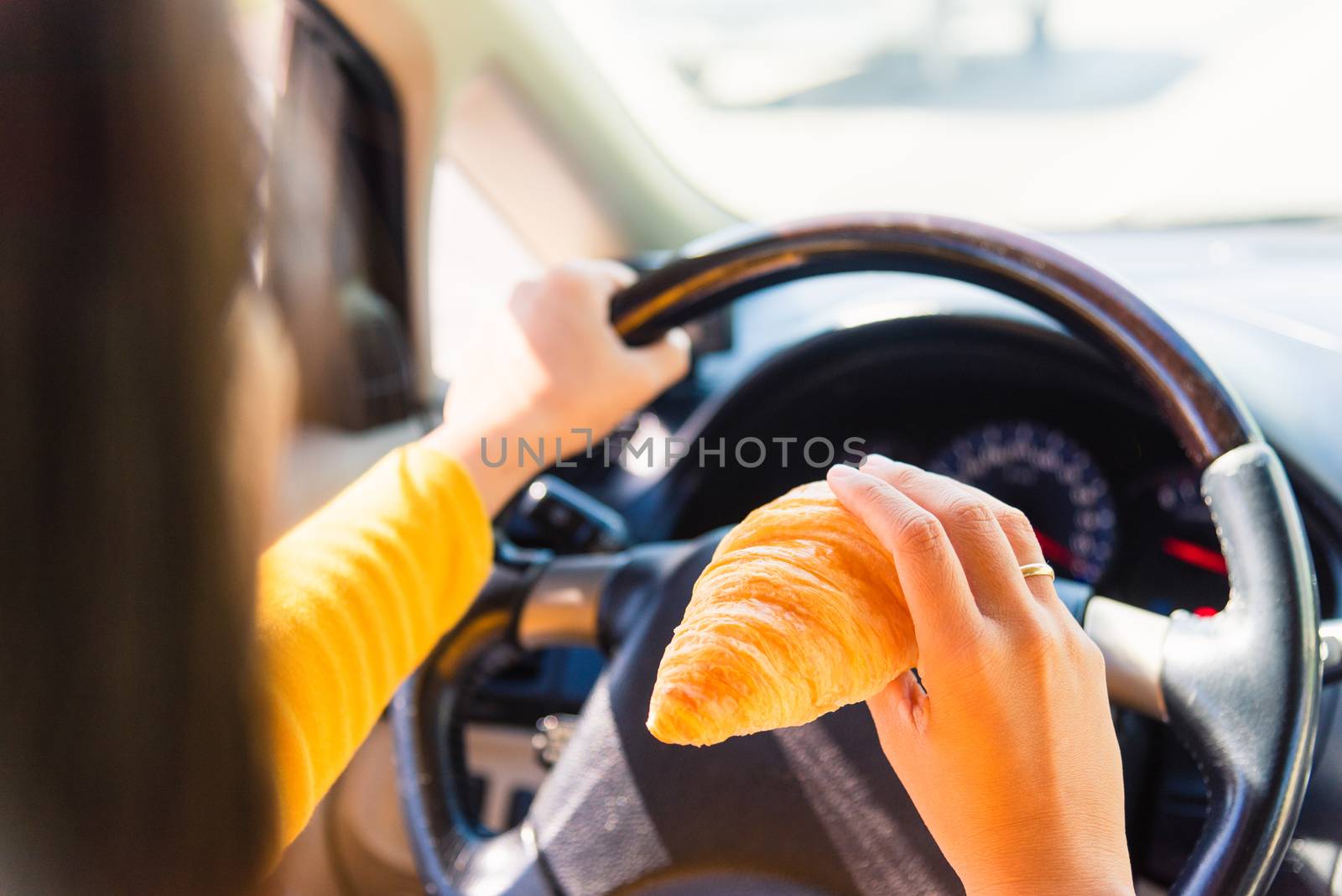 Asian woman eating food fastfood while driving the car in the morning during going to work on highway road, Transportation and vehicle concept