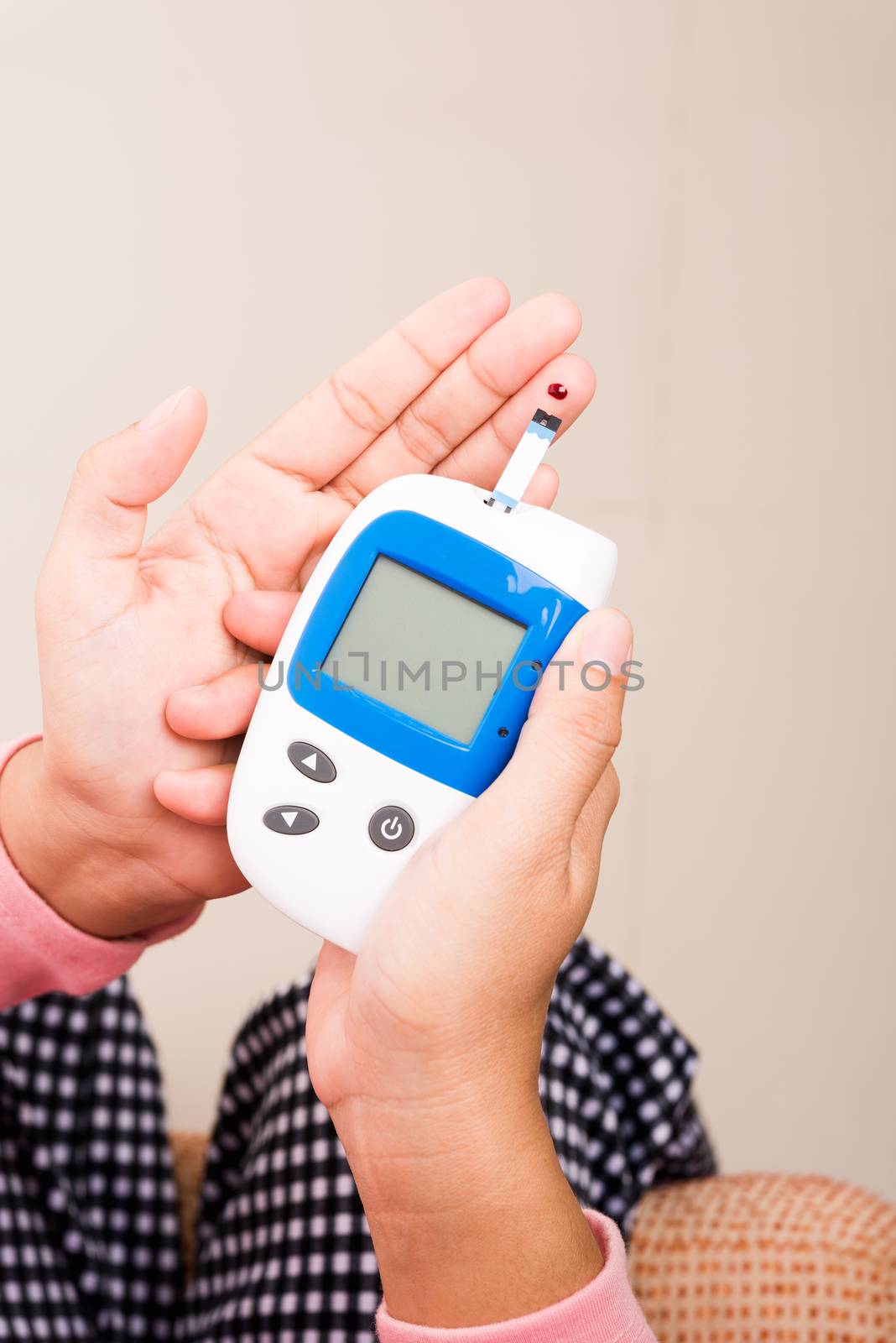 Closeup Hands woman measuring glucose test level check with blood on finger by glucometer at home she monitor and control high blood sugar diabetes and glycemic health care concept