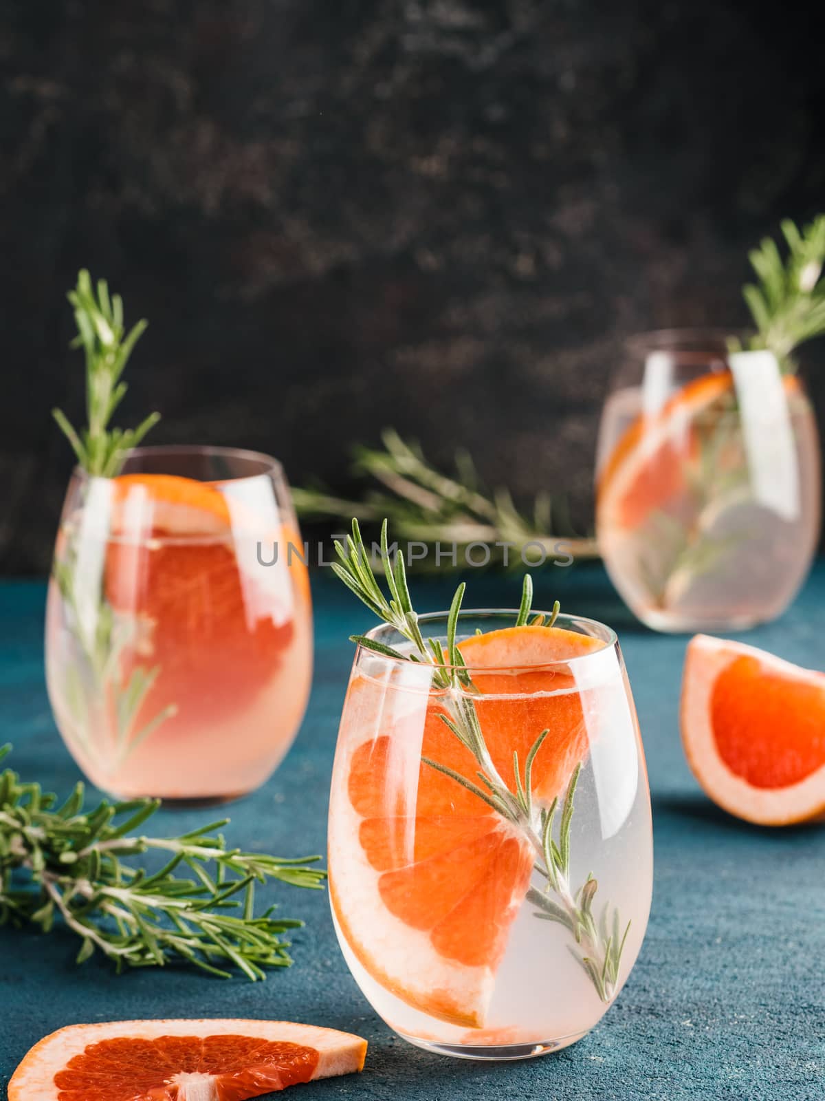 infused detox water or alcoholic or non-alcoholic cocktail with grapefruit and rosemary in glass on green and black cement background. healthy eating or holyday drink concept, copy space for text