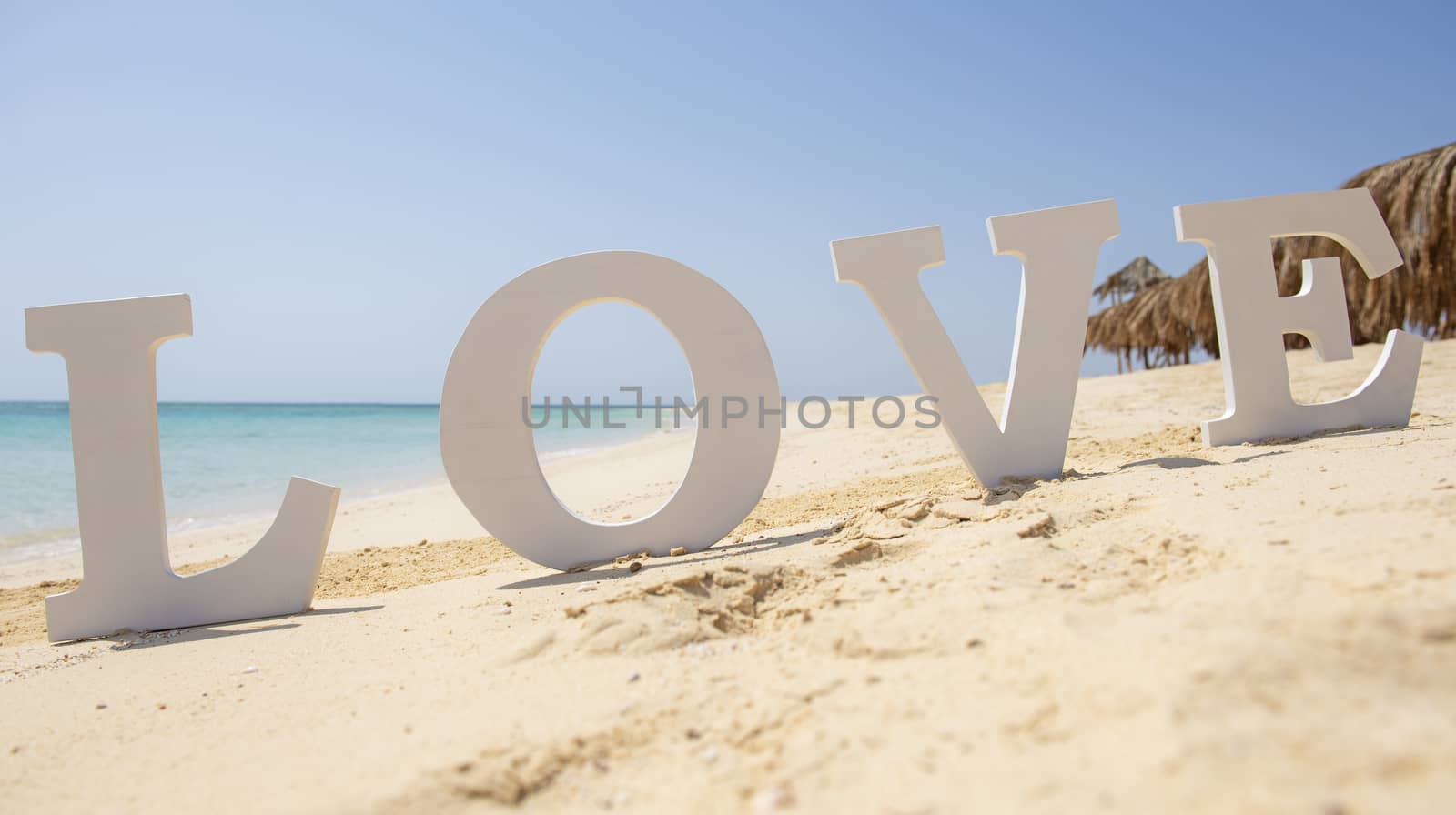 Closeup of romantic love sign on tropical island sandy beach paradise with ocean in background