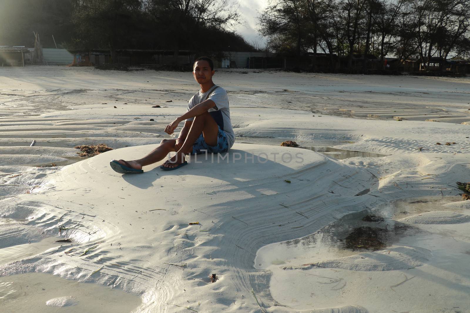 Teenager sitting on white sand at Tanjung Aan beach, Lombok, Ind by Sanatana2008