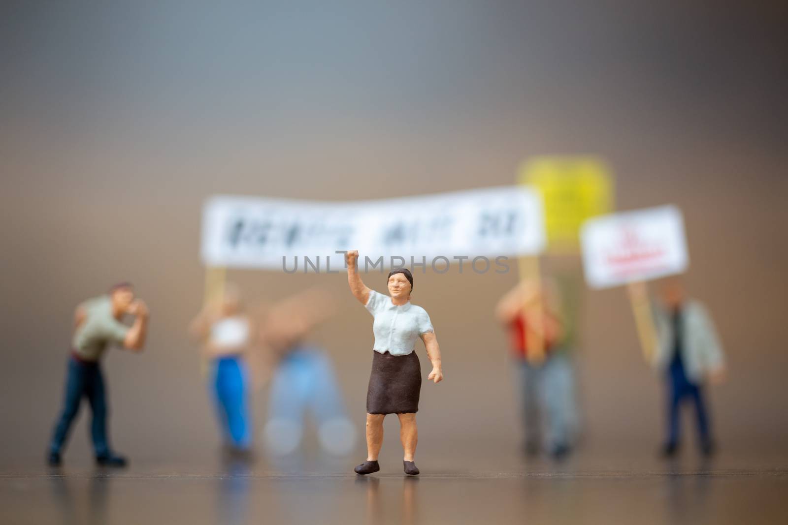 Miniature people , Crowd of protesters people raised hands and shouting on wooden background.