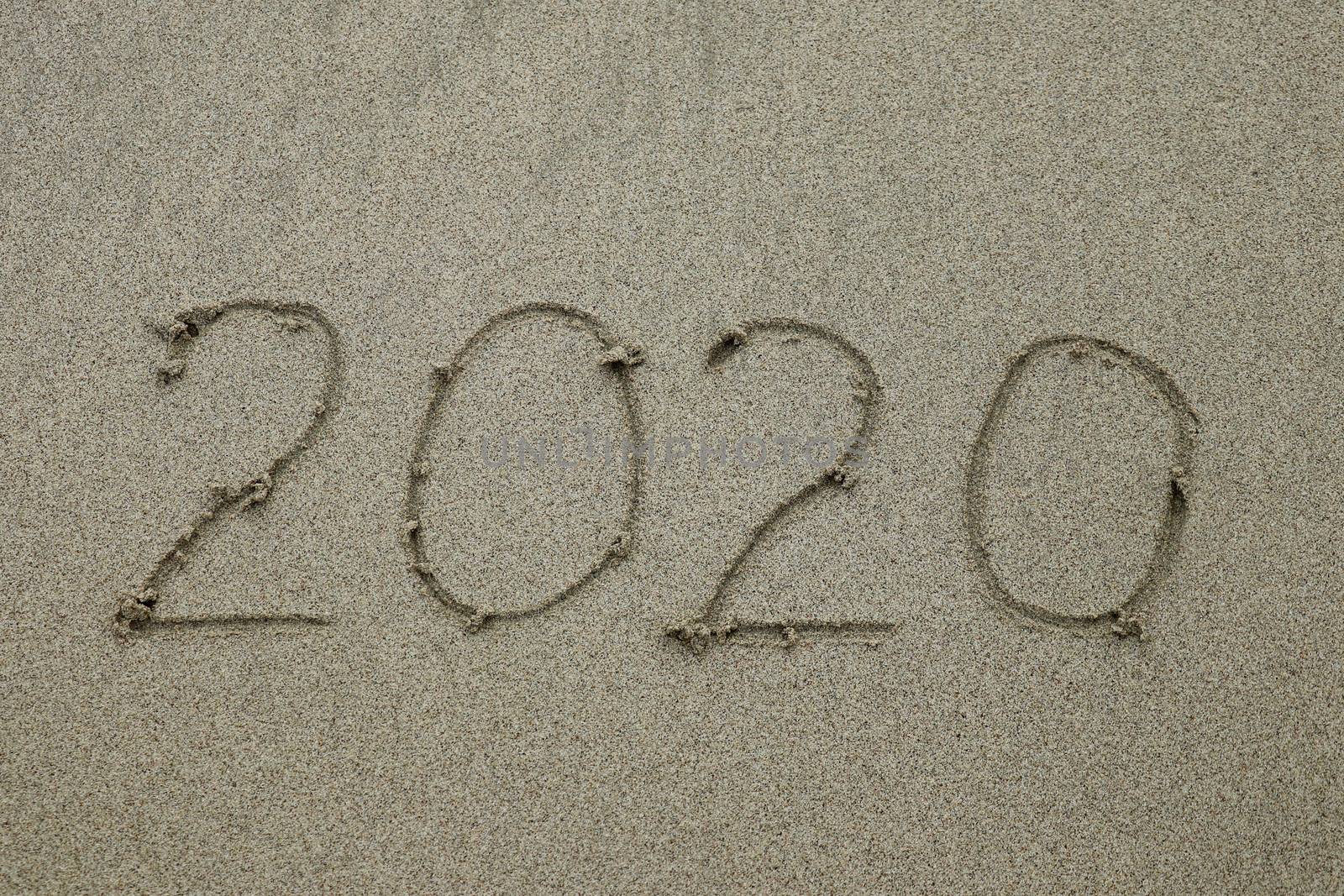 2020 drawn on the sand beach, new year concept. bye 2020 text is written by hand on the beach sand by Sanatana2008