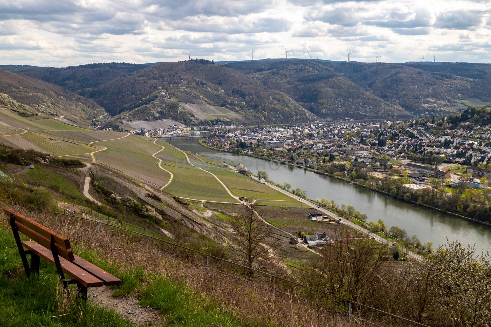 Panoramic view on the valley of the river Moselle and the city Bernkastel-Kues with a brown bench in the foregrouind