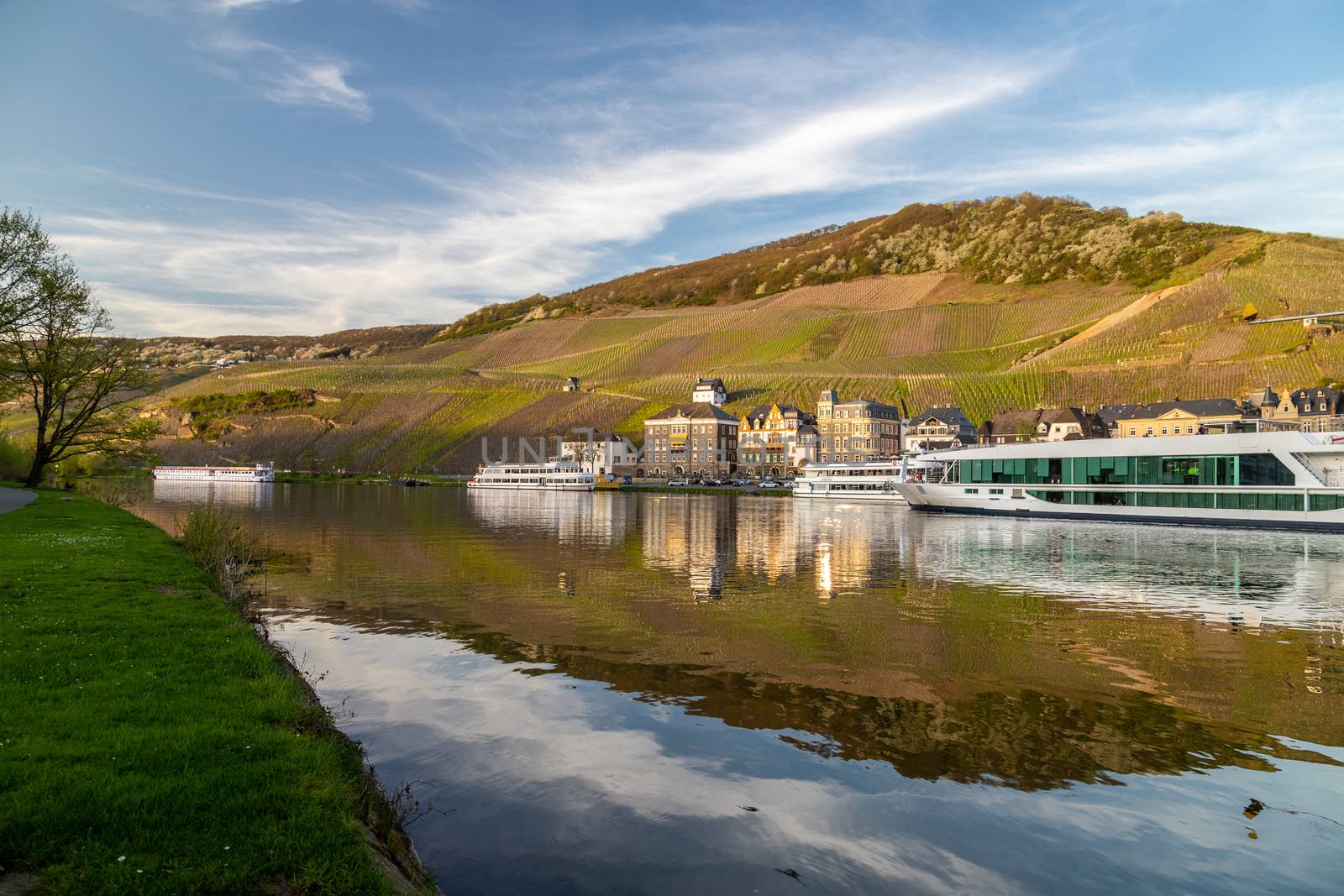 View at the city of Bernkastel-Kues at river Moselle with passenger ships and mountains with vineyards in the background