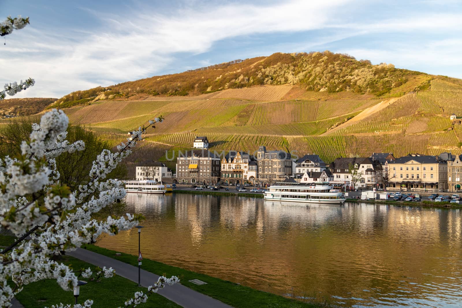 View at the city of Bernkastel-Kues at river Moselle with passenger ships and mountains with vineyards in the background
