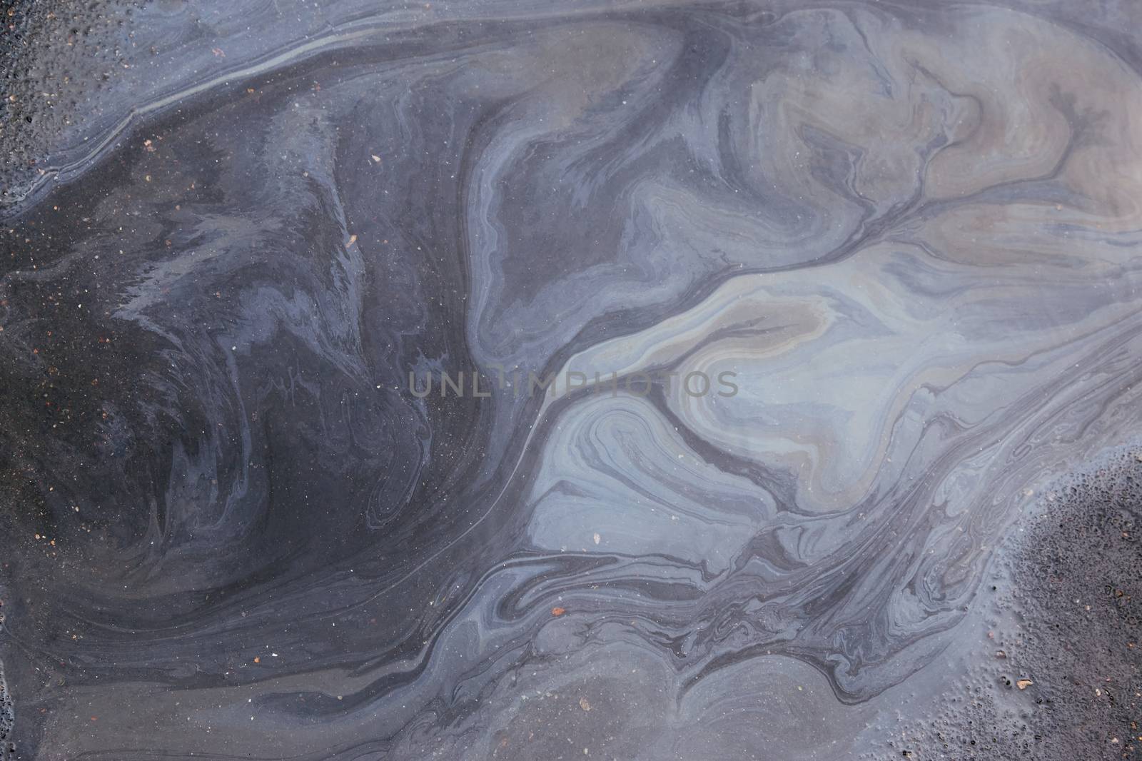Spills and oil pollution on the road Leads to beautiful patterns and colors.Color gasoline fuel spot on black asphalt, industrial details concept.