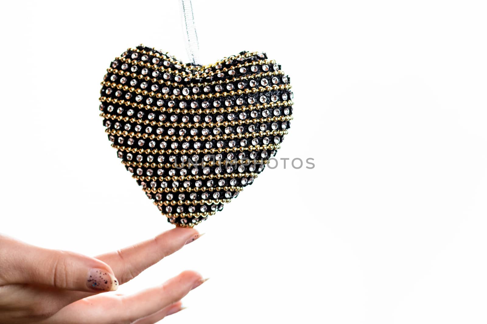 Hand holding heart shaped decoration isolated on white.