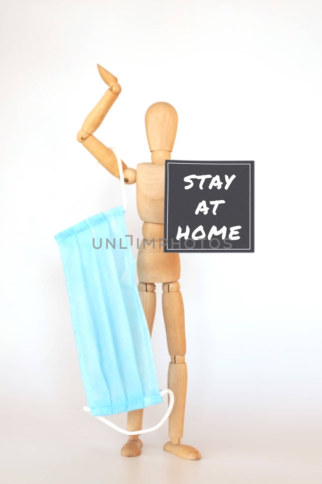 2019-ncov,World coronavirus pandemic. wooden man is isolated on a white background holds a medical protective mask and a sign saying: Stay home. Outbreak Defense Concept. Copy Space.