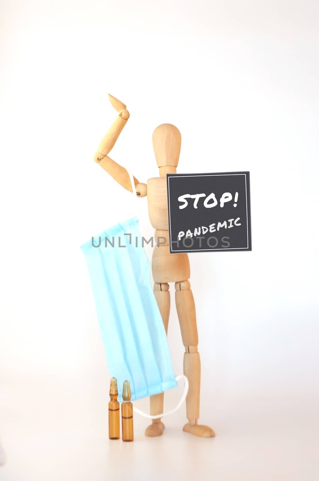 World epidemic of coronavirus. wooden man is isolated on a white background holds a medical protective mask and a sign that says: stop, pandemic. Outbreak Defense Concept. Copy Space.